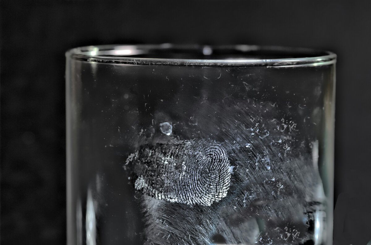 Person holding a glass of water with fresh herbs on a table, representing natural treatment for hemorrhagic cystitis