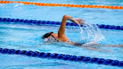 Woman swimming laps in an outdoor pool, staying active for bladder health